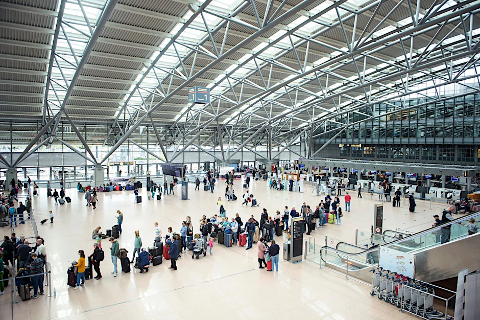 dpatopbilder - Reisende stehen im Terminal des Flughafens Hamburg in einer Warteschlange an einem Check-in-Schalter.  