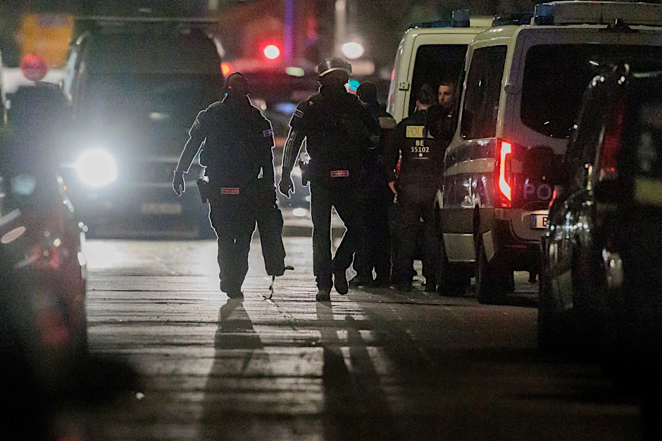 Polizisten gehen zu den Einsatzfahrzeugen nach der Beendigung einer Geiselnahme in einem Geschäft an der Keithstraße.  