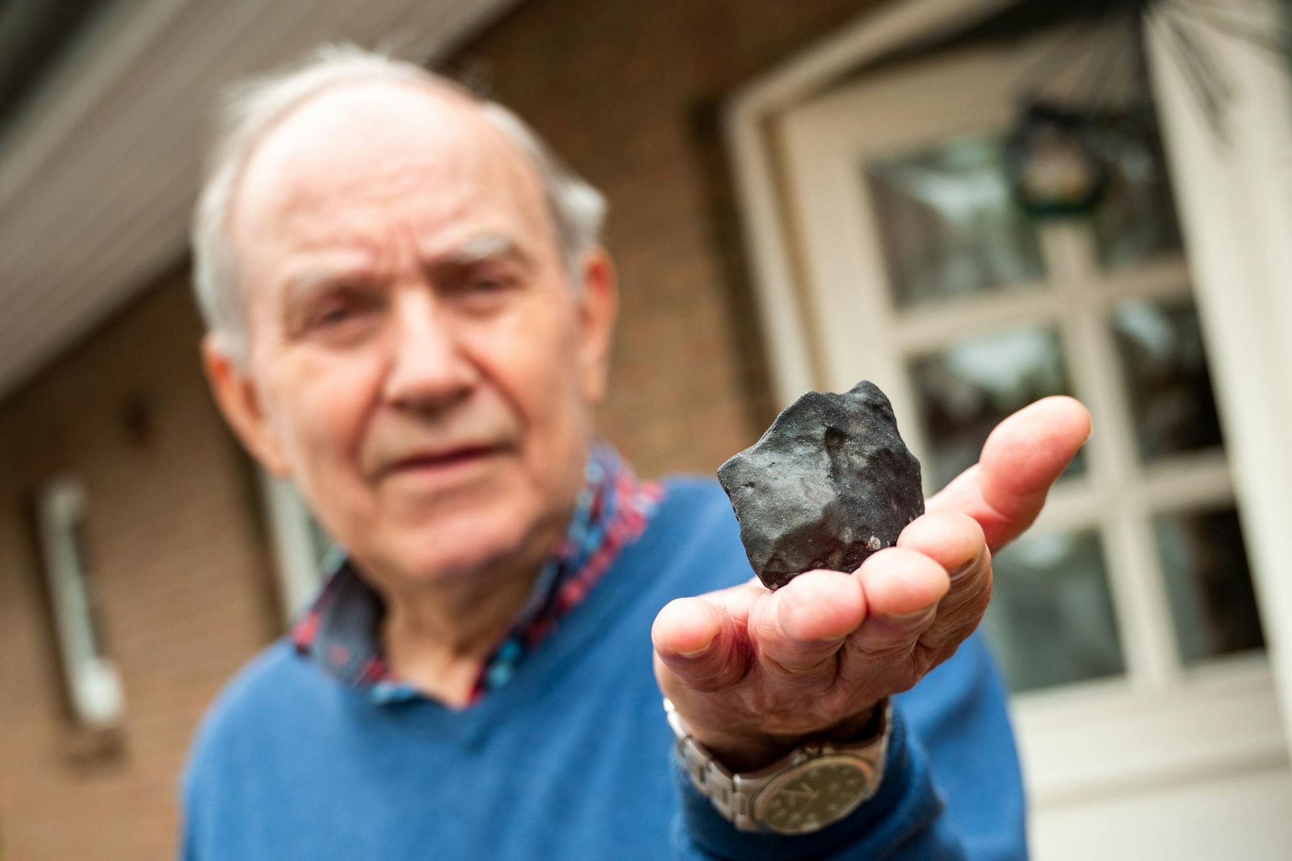 Hausbesitzer Wilfried Labusch hält vor seinem Haus einen kleinen Meteoriten in der Hand, der in sein Dach eingeschlagen ist.