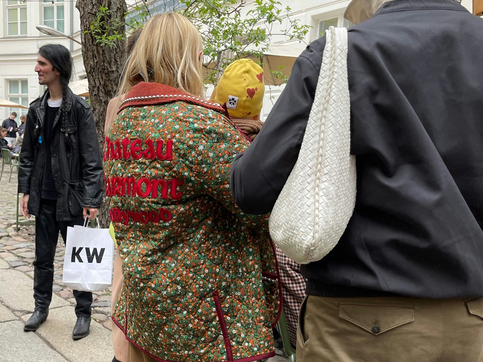 Viel los im Hof der Kunstwerke: geflochtene Zöpfe, eine Gucci-Jacke mit Chateau-Marmont-Stickerei auf dem Rücken und eine Tasche von Bottega Veneta