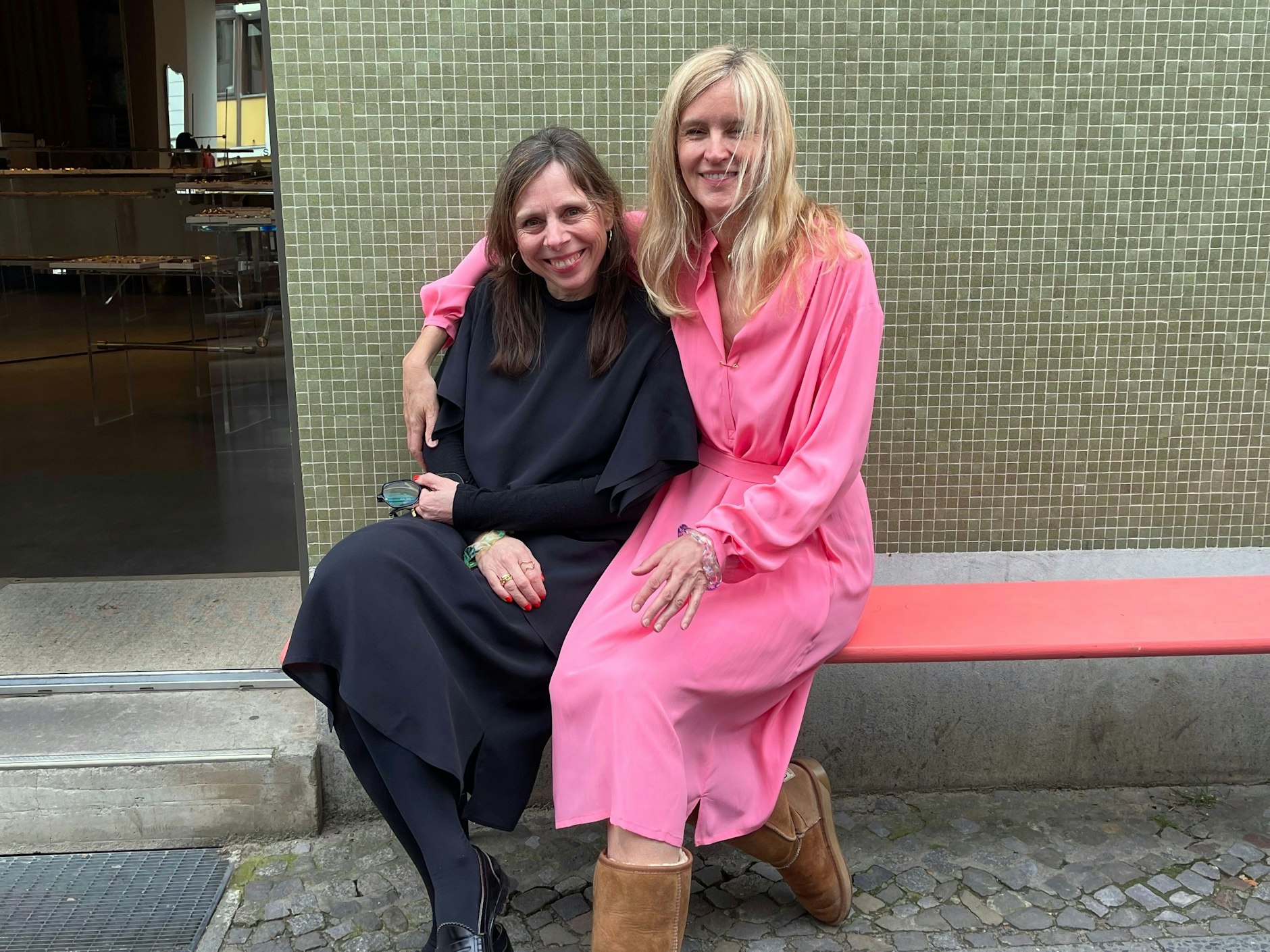 Sabrina Dehoff (links), umarmt von der Modeprofessorin Grit Seymour, die gerade ein pinkes Kleid aus der aktuellen Kollektion anprobiert. Am Handgelenk tragen beide gläserne Armreife einer neuen Schmucklinie, die Sabrina Dehoff anlässlich des Gallery Weekends gelauncht hat.