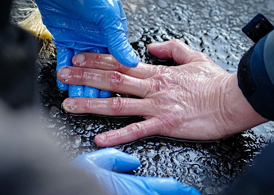 Ein Polizeibeamter löst die Hand eines Klimaaktivisten von der Straße.  