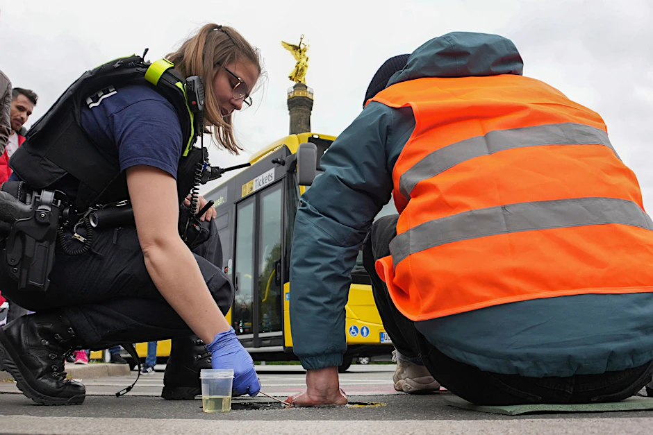 Eine Polizistin versucht die Hand eines Aktivisten von der Fahrbahn zu lösen.