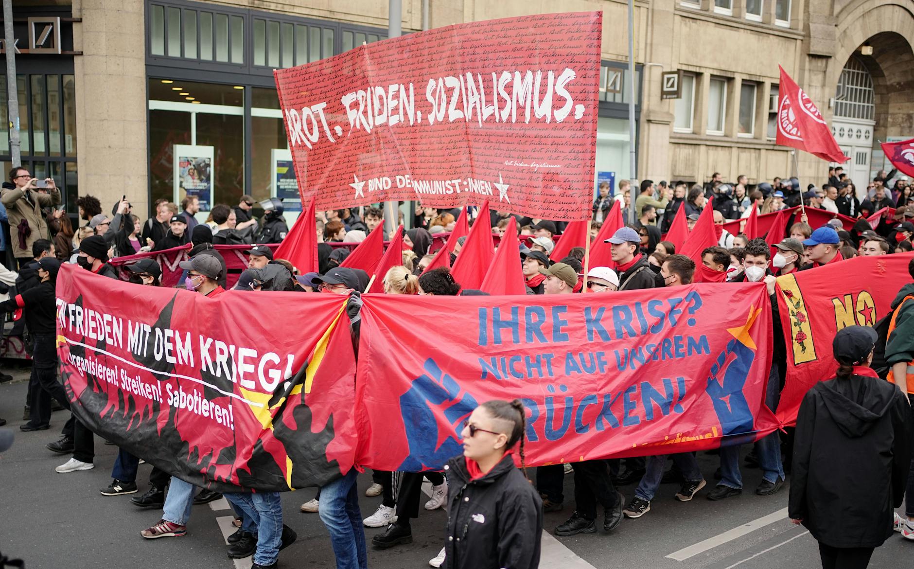 01.05.2023, Berlin: Demonstranten halten ein Banner mit dem Schriftzug Brot. Frieden. Sozialismus beim Protestzug hoch.