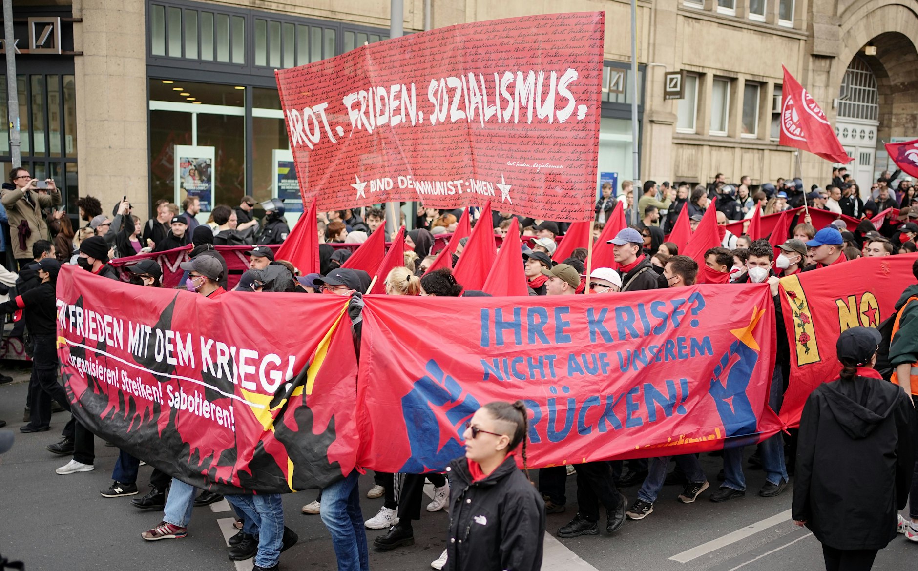01.05.2023, Berlin: Demonstranten halten ein Banner mit dem Schriftzug Brot. Frieden. Sozialismus beim Protestzug hoch.