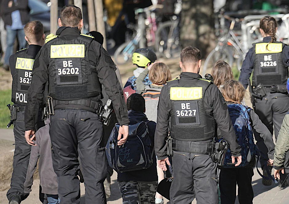 Polizisten geleiten Kinder weg vom Tatort an der Schule in Berlin-Neukölln.