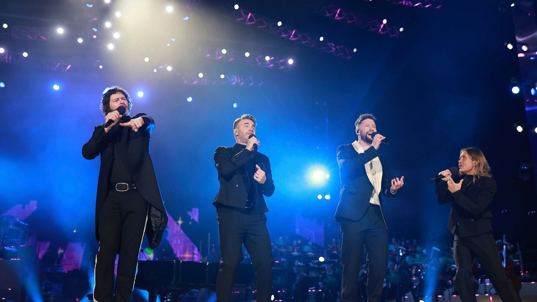 Gary Barlow, Howard Donald and Mark Owen von Take That traten mit dem Pop-Sänger Calum Scott (re.) auf.