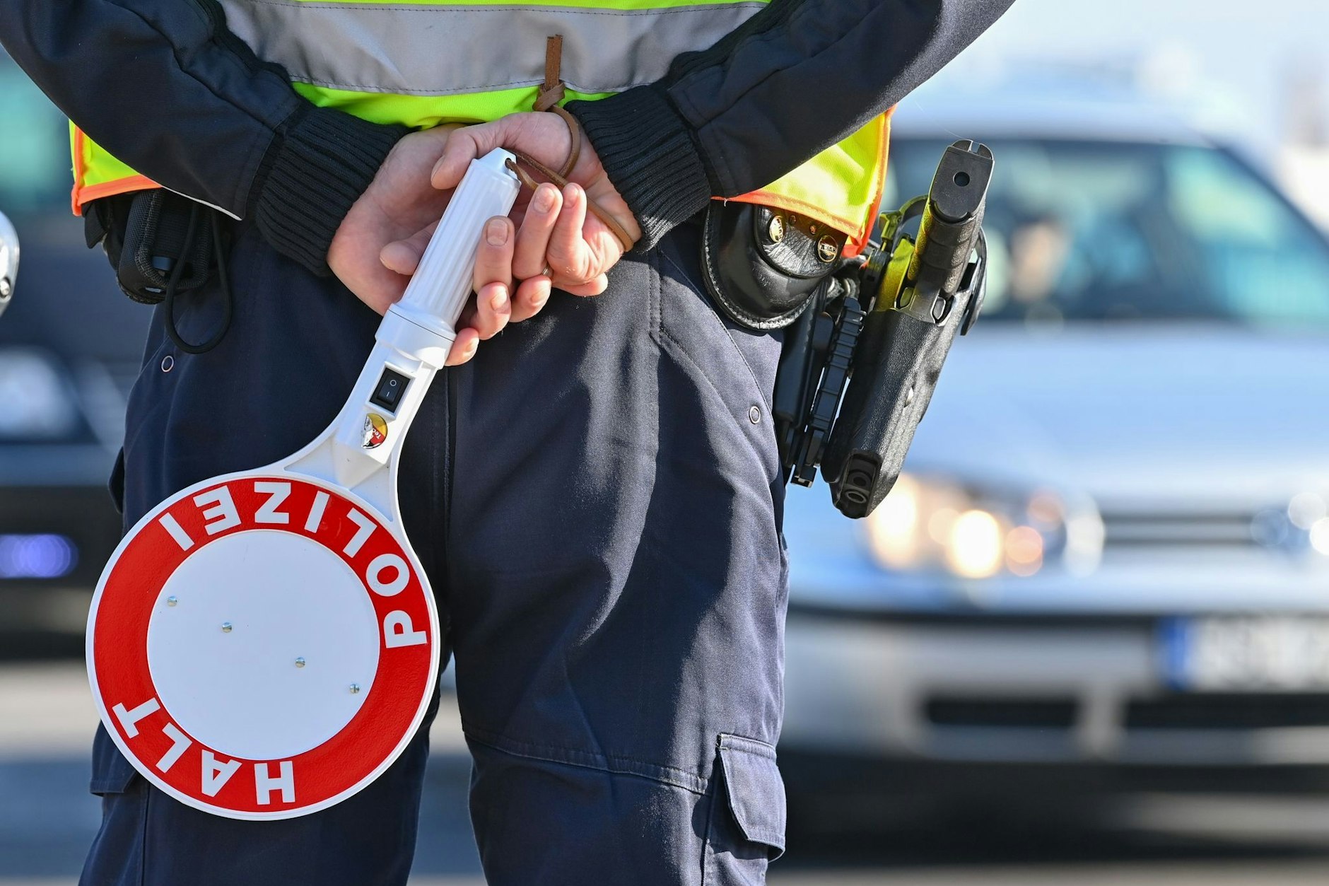 Ein Polizeibeamter hält eine Winkerkelle in den Händen. 