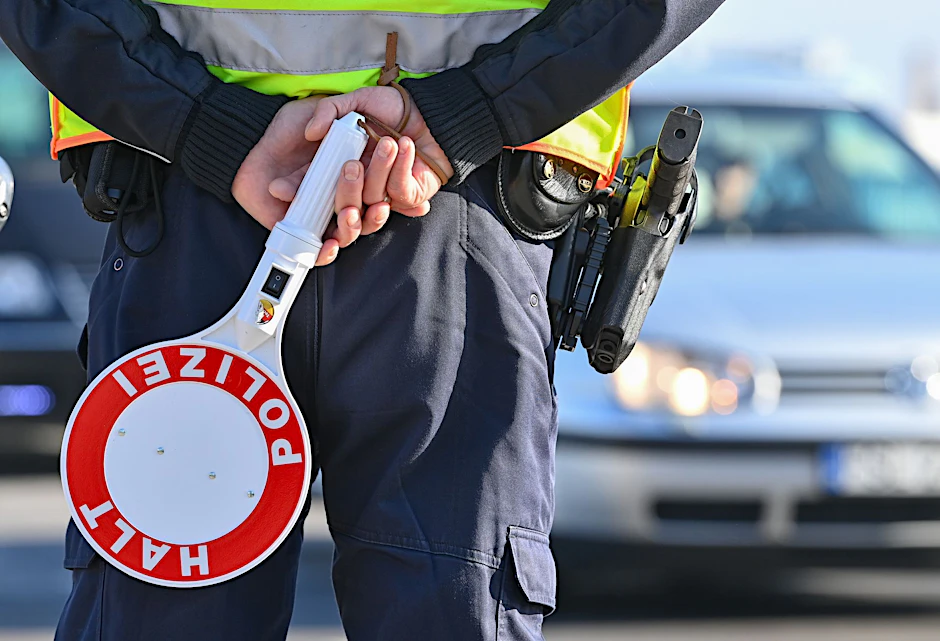 Ein Polizeibeamter hält eine Winkerkelle in den&nbsp;Händen.&nbsp;