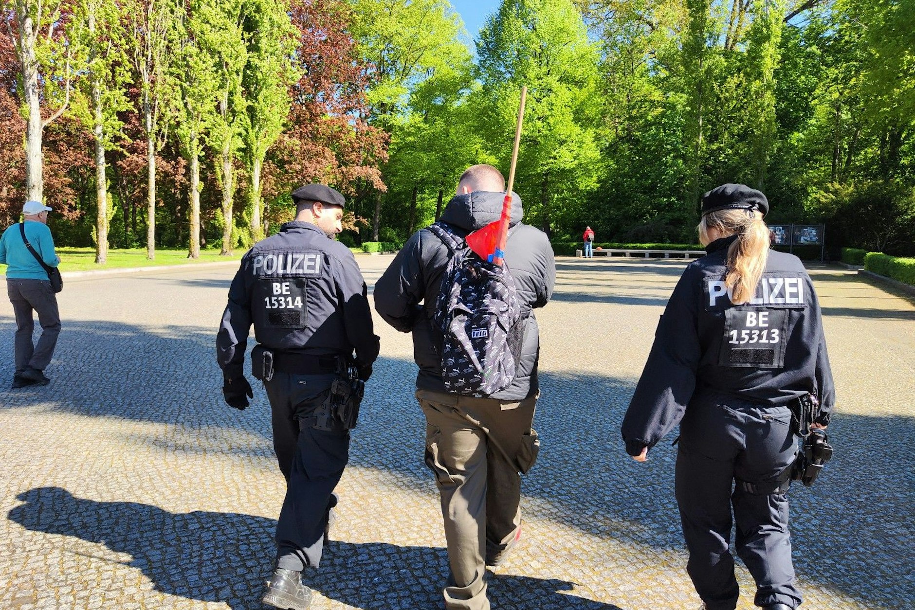 Ein Mann mit einer verbotenen Fahne wird von der Polizei vom Platz geführt.
