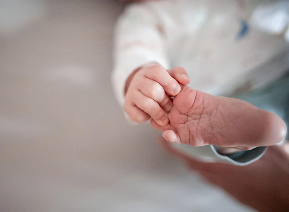 ARCHIV - Baby greift nach seinem Fuß.  