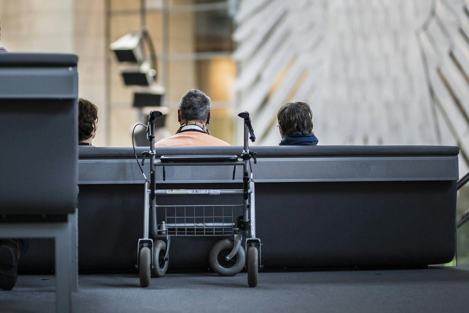 Ein Rollator steht hinter einem Senior während einer Plenardebatte im Bundestag. Karl Lauterbachs geplante Pflegereform stößt auf Kritik.