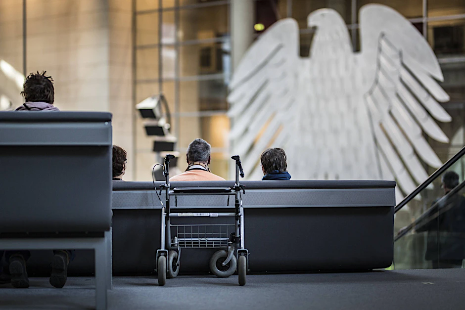 Ein Rollator steht hinter einem Senior während einer Plenardebatte im Bundestag. Karl Lauterbachs geplante Pflegereform stößt auf Kritik.