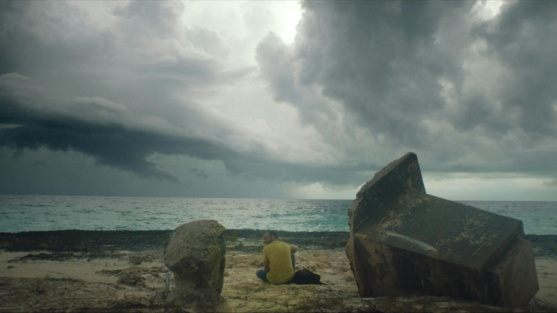 Eine Szene aus dem Film „Ernesto’s Island“: Die Hauptfigur des Films, der Berliner Matthias (Max Riemelt), hat die DDR-Insel erreicht. Dunkle Wolken ziehen am Horizont auf.