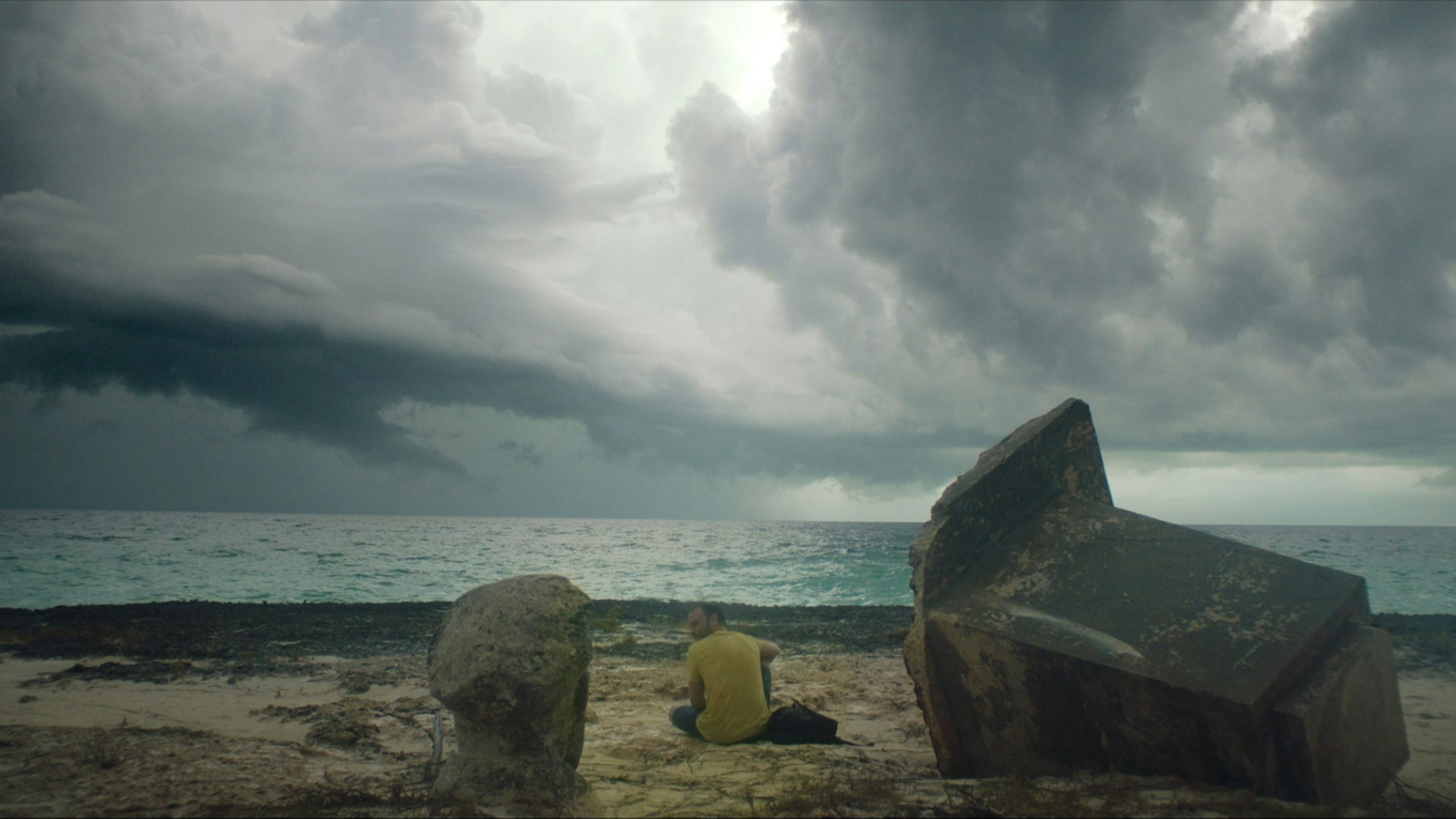 Eine Szene aus dem Film „Ernesto’s Island“: Die Hauptfigur des Films, der Berliner Matthias (Max Riemelt), hat die DDR-Insel erreicht. Dunkle Wolken ziehen am Horizont auf.
