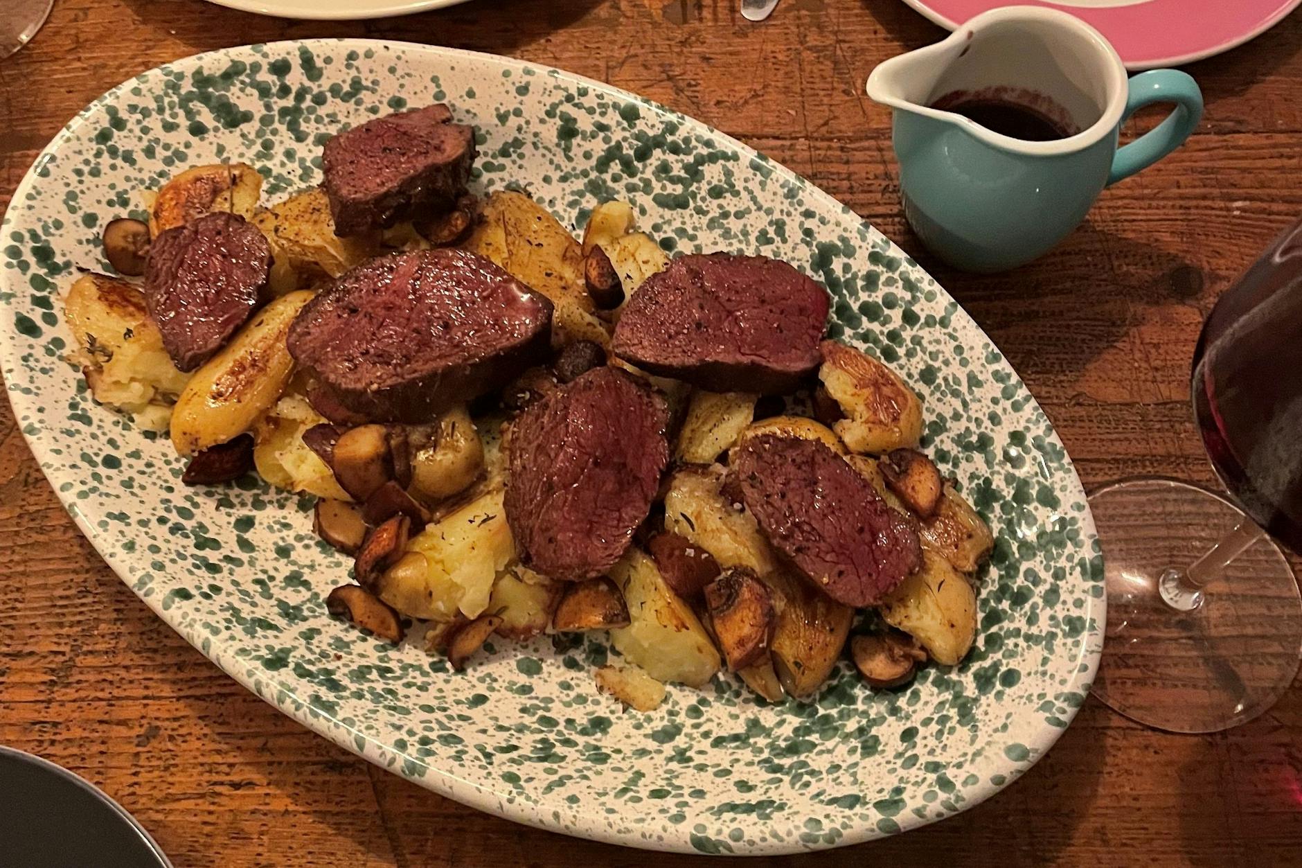 Ein schön rosig gebratenes Hirsch-Steak mit Kartoffeln, Pilzen und Rotwein-Velouté.