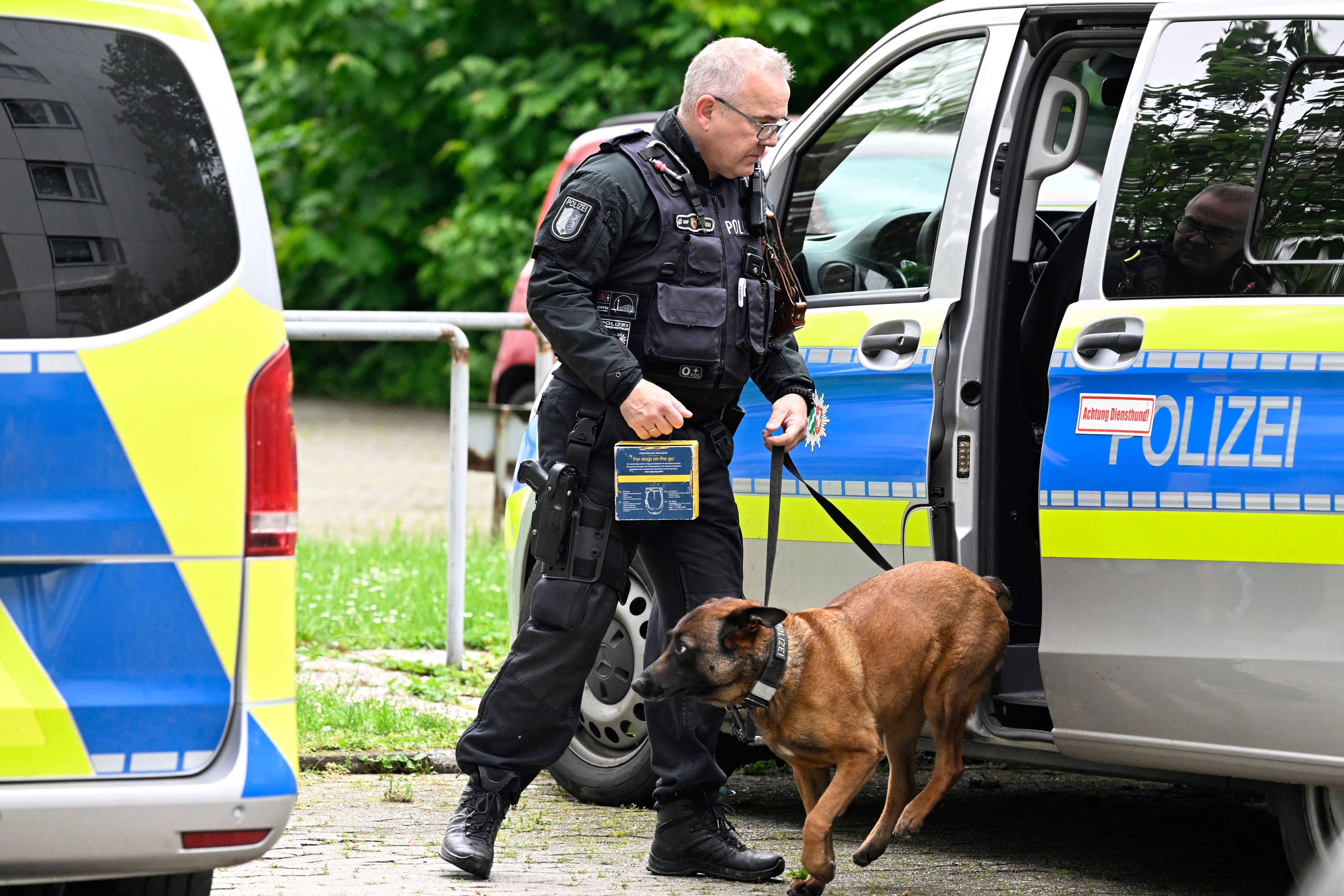 Ein Polizist führt einen Spurensuchhund an den Tatort in einem Hochhaus.