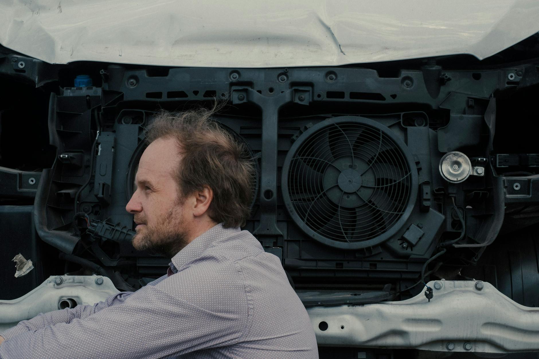 Conrad Kunze sitzt vor einem demolierten Auto.