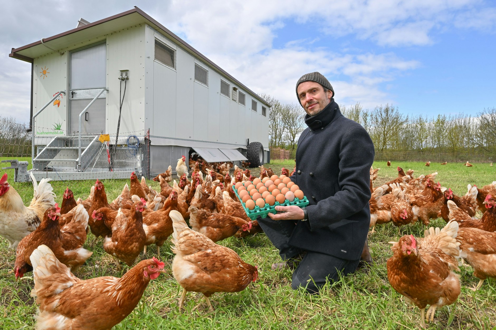Ludwig Seeger, Initiator der Bürgergut-Genossenschaft, hockt mit frischen Eiern vor einem Hühnermobil vom Bürgergut Börnicke. Genossenschaftler finanzieren die ökologische Bewirtschaftung von etwa elf Hektar Land, ein Hühnermobil die externe Beweidung mit Rindern.