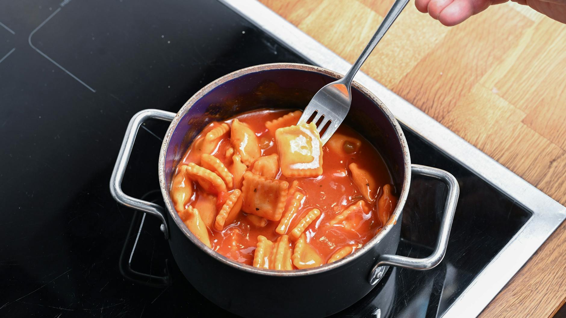 Ein Topf mit Ravioli aus der Dose steht auf einem Herd.
