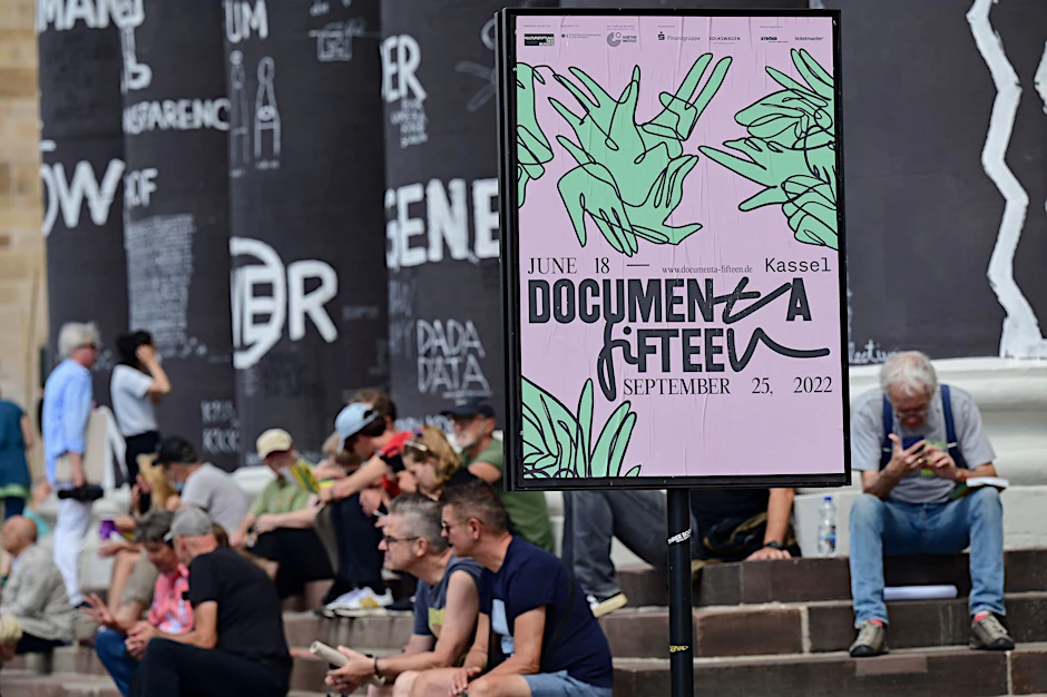 Besucher der Documenta Fifteen sitzen auf den Stufen des Fridericianums in Kassel.