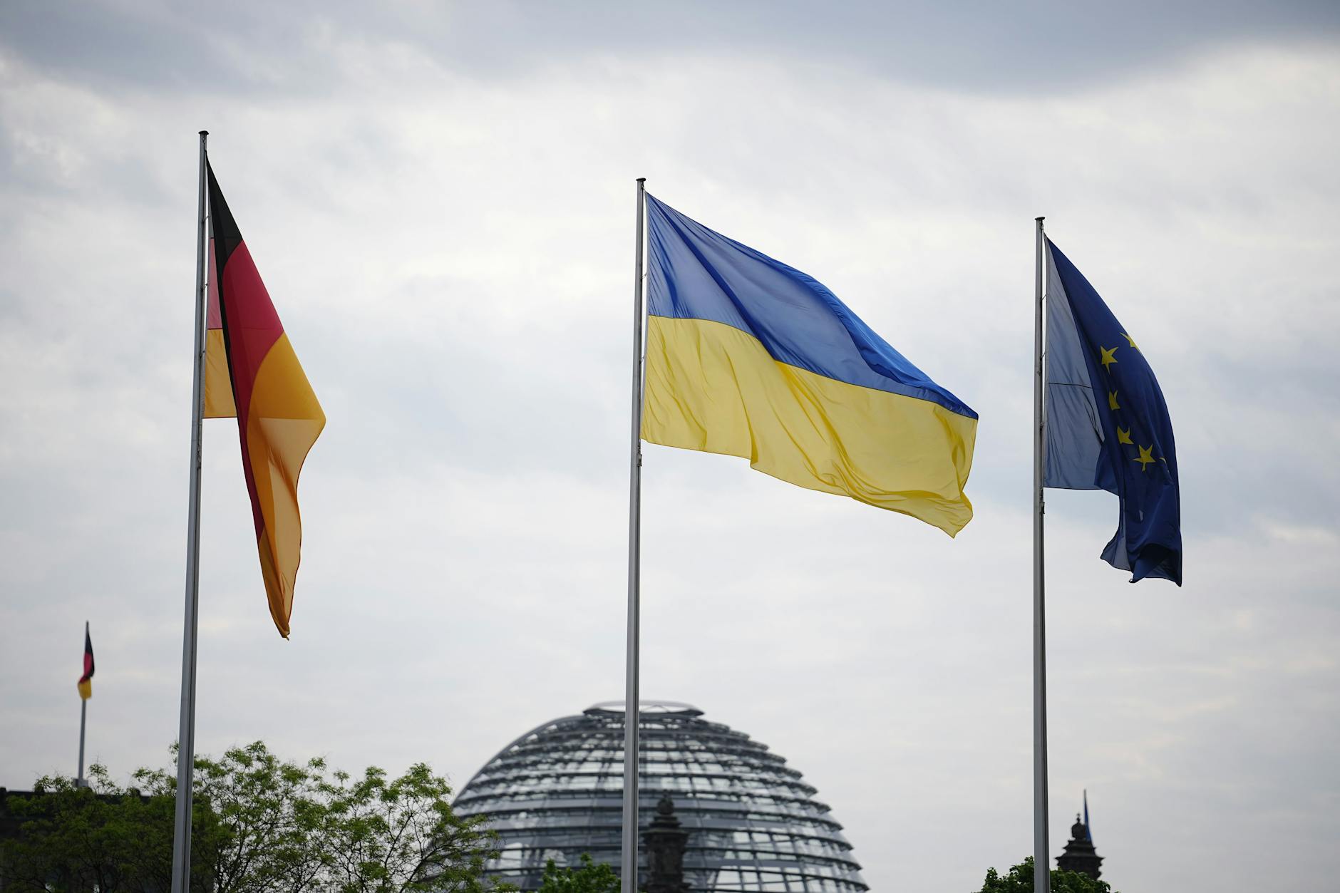 Die Fahnen von Deutschland, der Ukraine und Europa wehen vor dem Bundeskanzleramt im Wind.