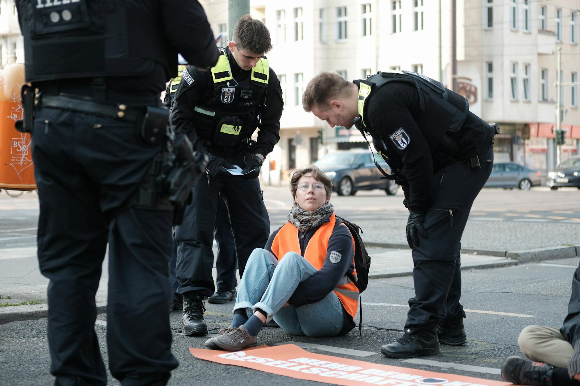 Eine Aktivistin klebt sich an die Greifswalder Str. in Berlin.