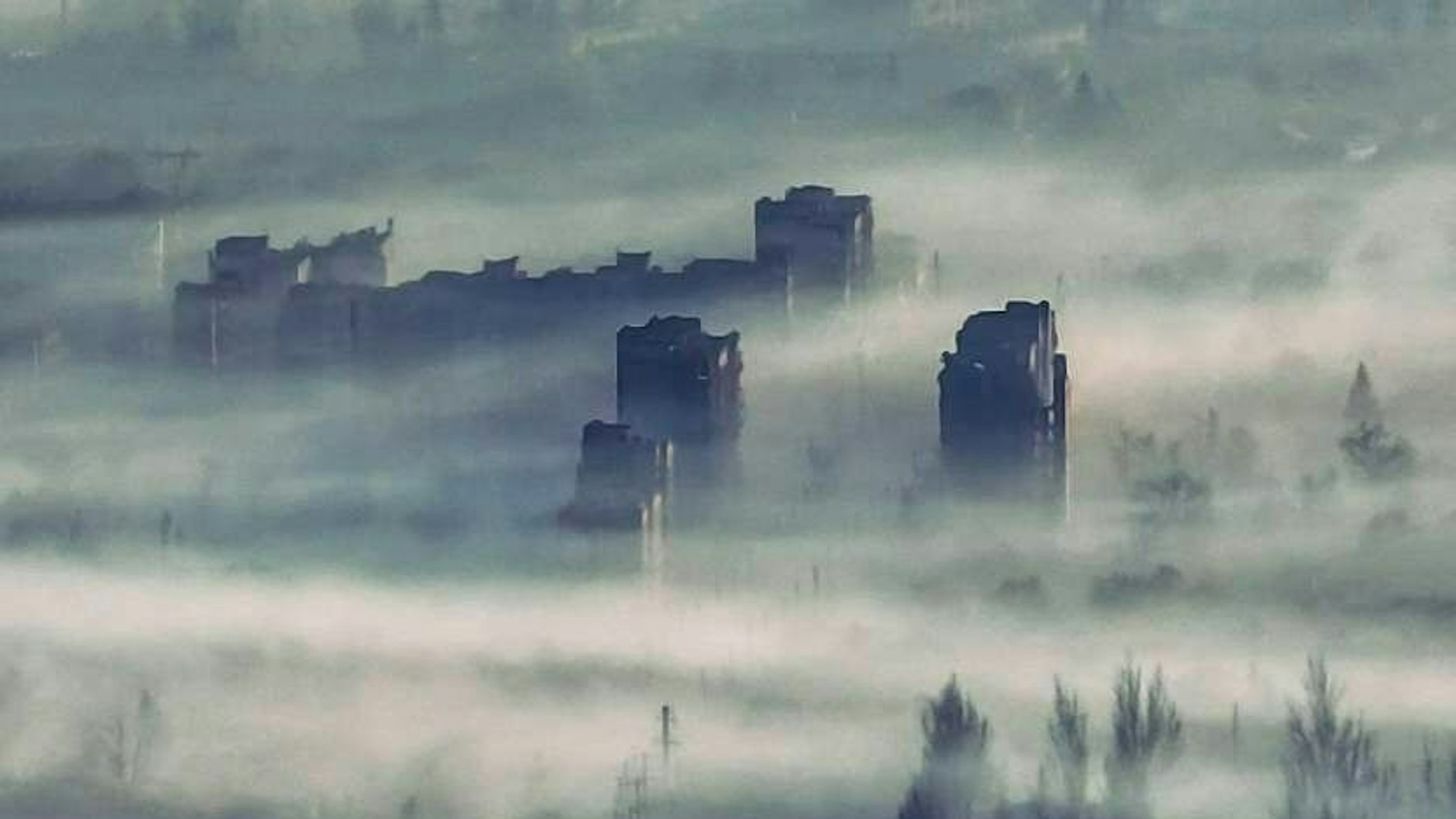 Die Gerippe der Plattenbauten ragen aus dem Rauch.