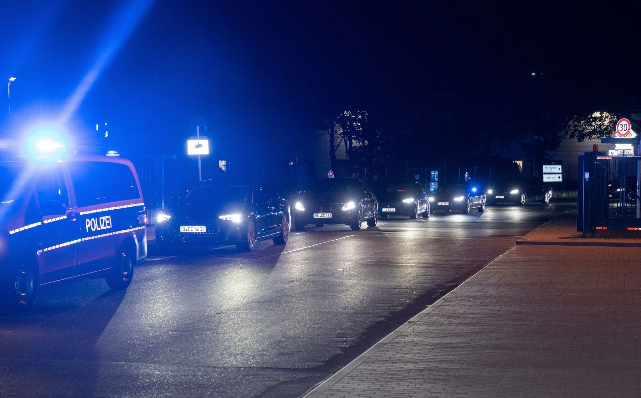 Einsatzfahrzeuge der Polizei, Limousinen und gepanzerte Fahrzeuge verlassen das Gelände des Flughafen Schönefeld.  