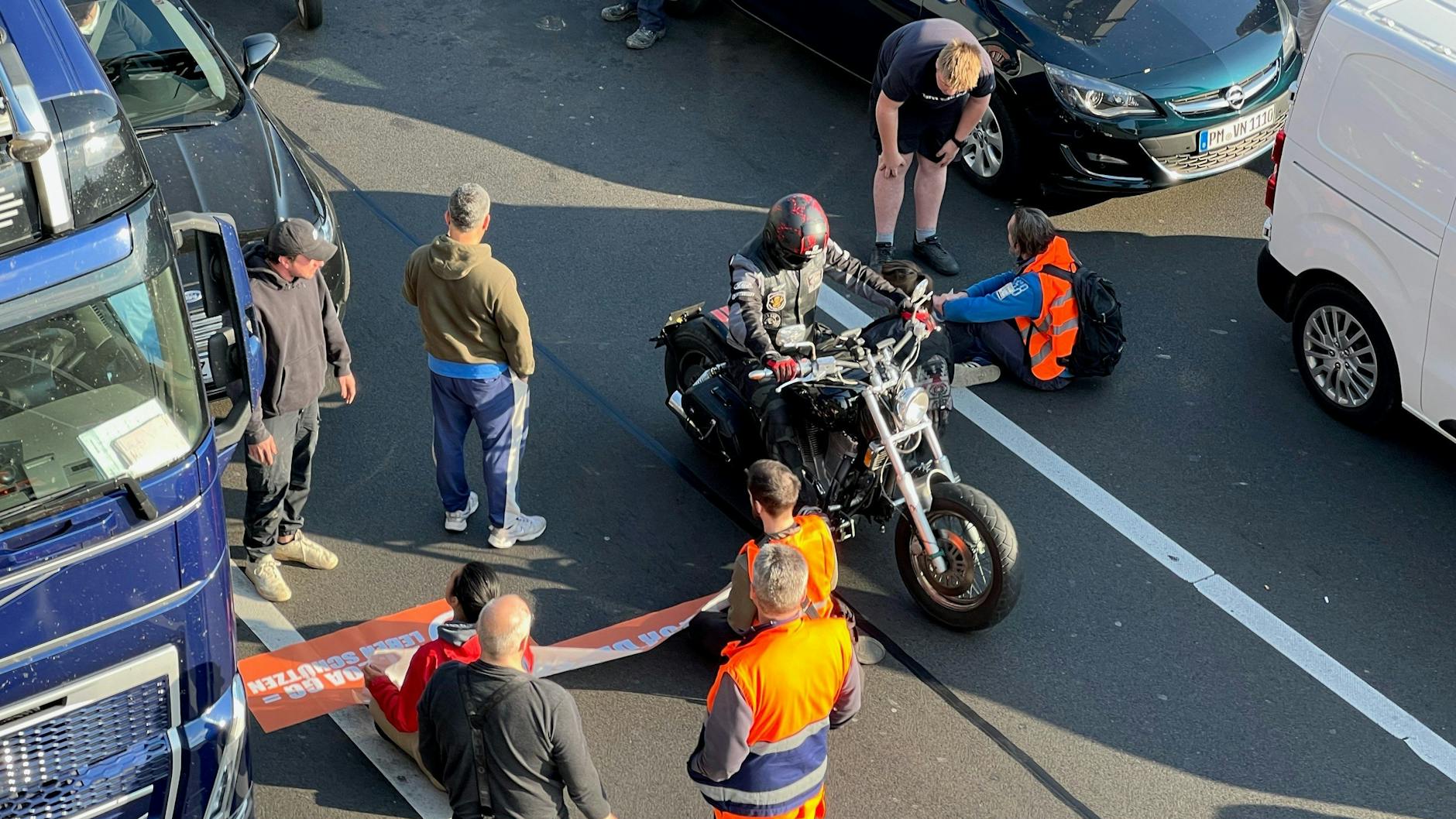 Klima-Kleber blockieren die A100 am Hohenzollerndamm. Ein Biker durchfährt die Absperrung.