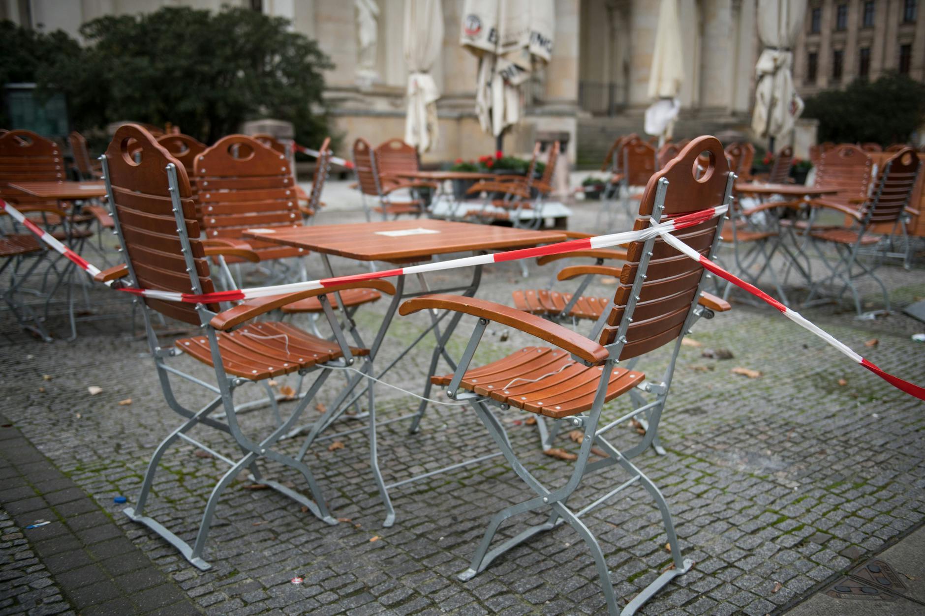 Ein Absperrband über Stühlen und Tischen vor einem Gastronomiebetrieb am Gendarmenmarkt in Berlin-Mitte