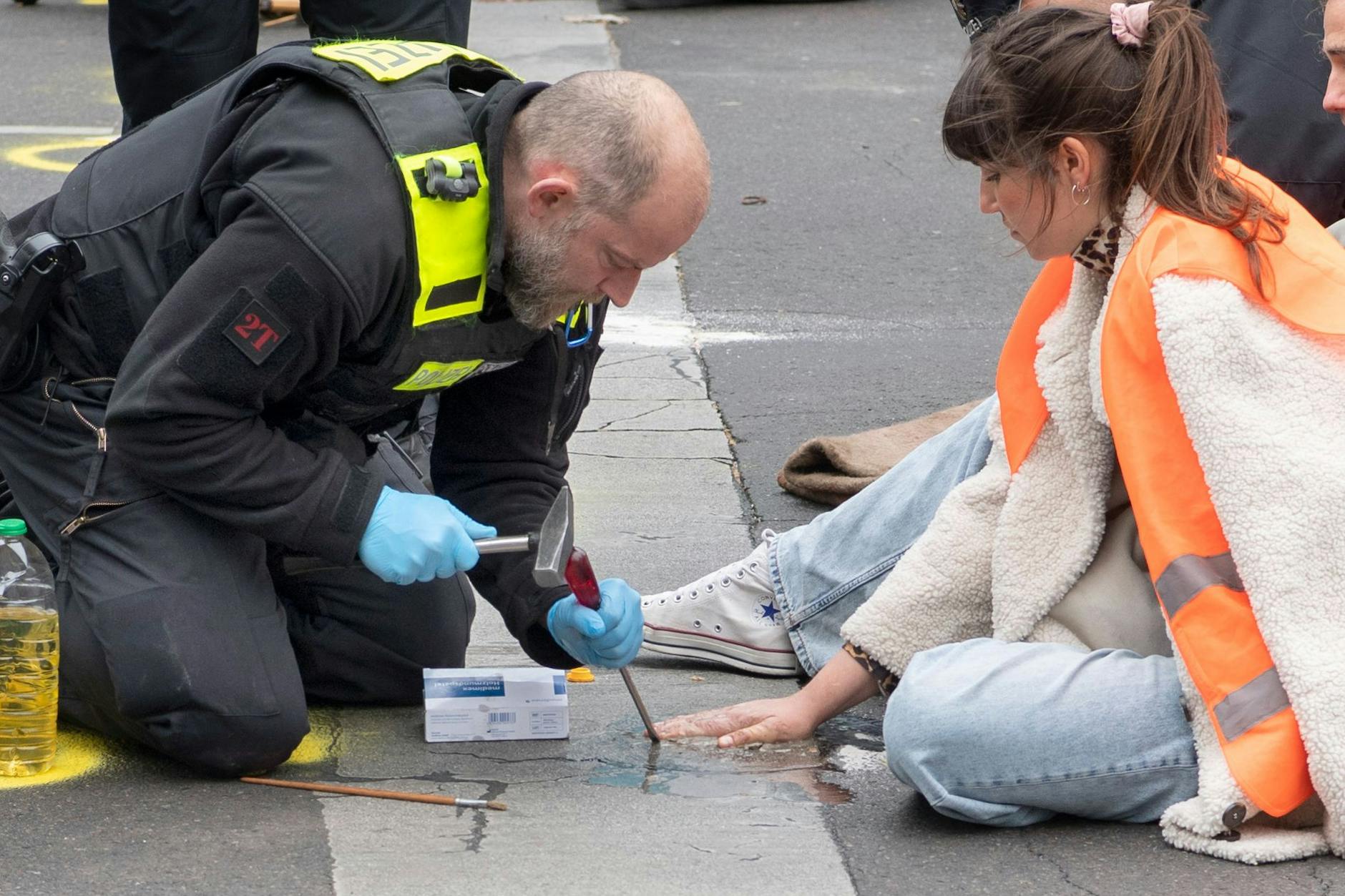 Polizisten versuchen in Berlin bei einer Straßenblockade der Letzten Generation Carla Hinrichs von der Straße zu lösen. 