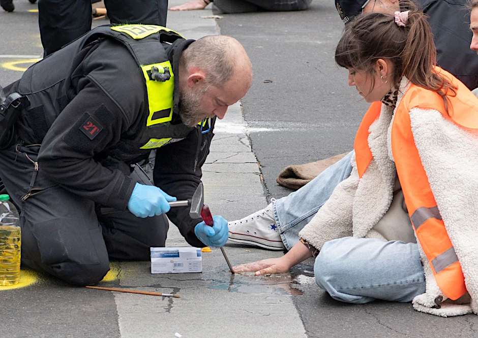 Polizisten versuchen in Berlin bei einer Straßenblockade der Letzten Generation Carla Hinrichs von der Straße zu lösen.&nbsp;
