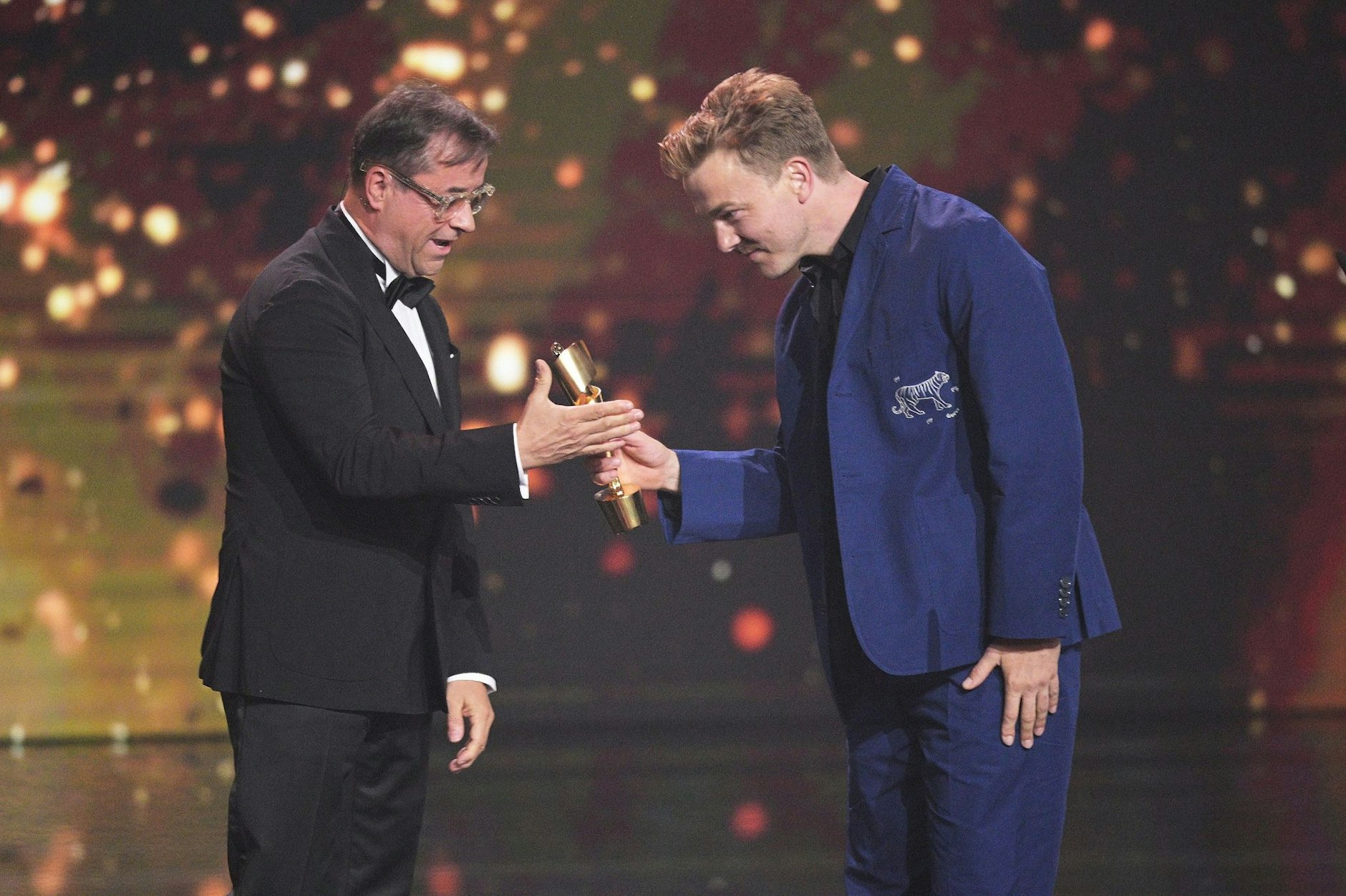 Schauspieler Albrecht Schuch (r) bekommt bei der Verleihung des Deutschen Filmpreises den Preis für die beste männliche Nebenrolle von Jan Josef Liefers überreicht.  