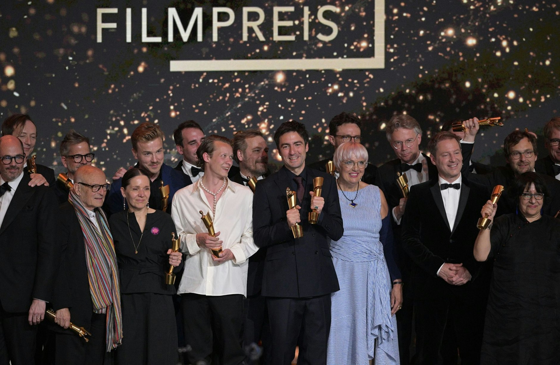 Zusammen mit Kulturstaatsministerin Claudia Roth (im blau-weiß gestreiften Kleid) stehen die Preisträger des Deutschen Filmpreises auf der Bühne.