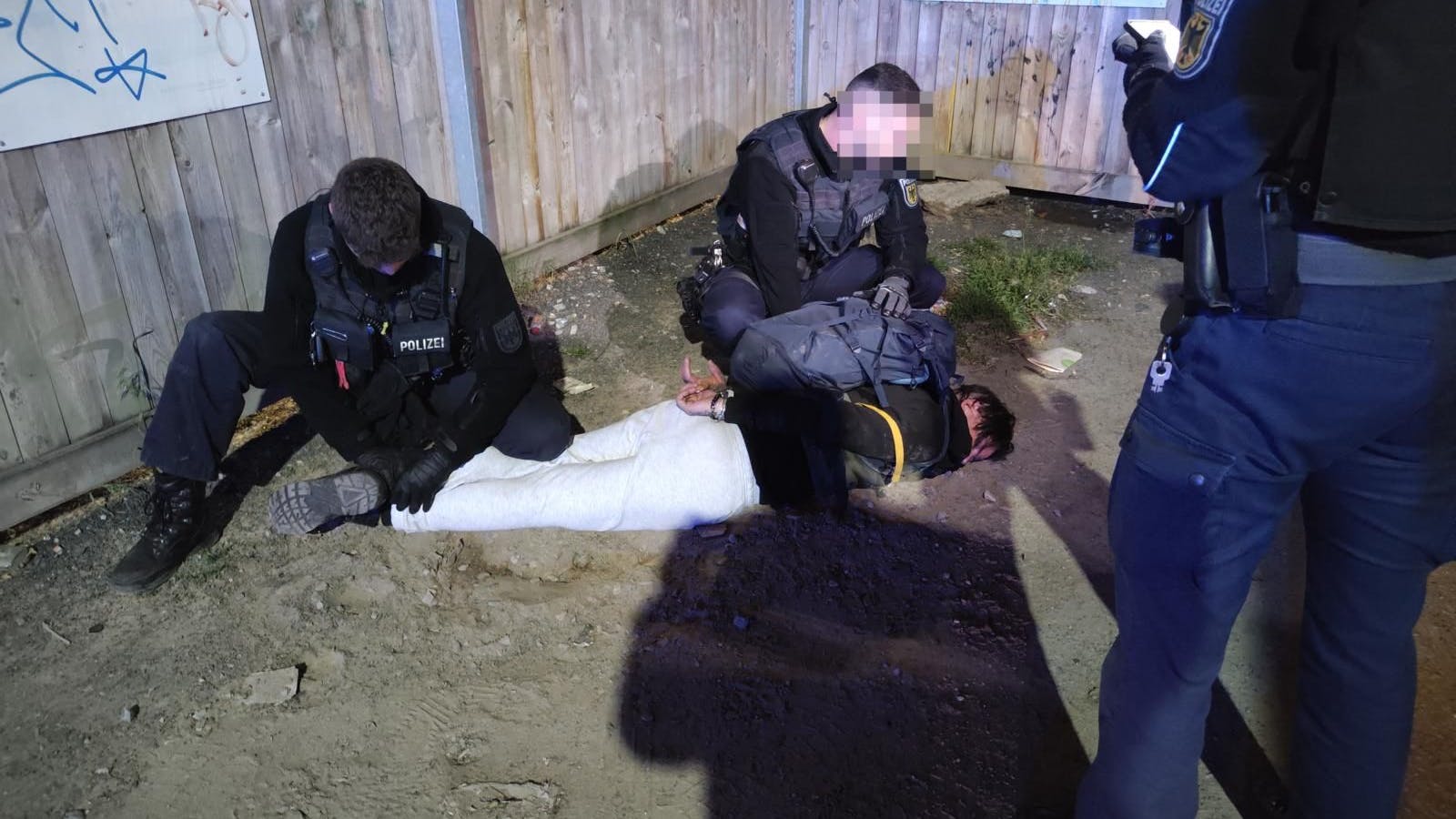 Polizeibeamte halten eine mutmaßliche Tatbeteiligte nach der Attacke in Schöneweide in Schach.