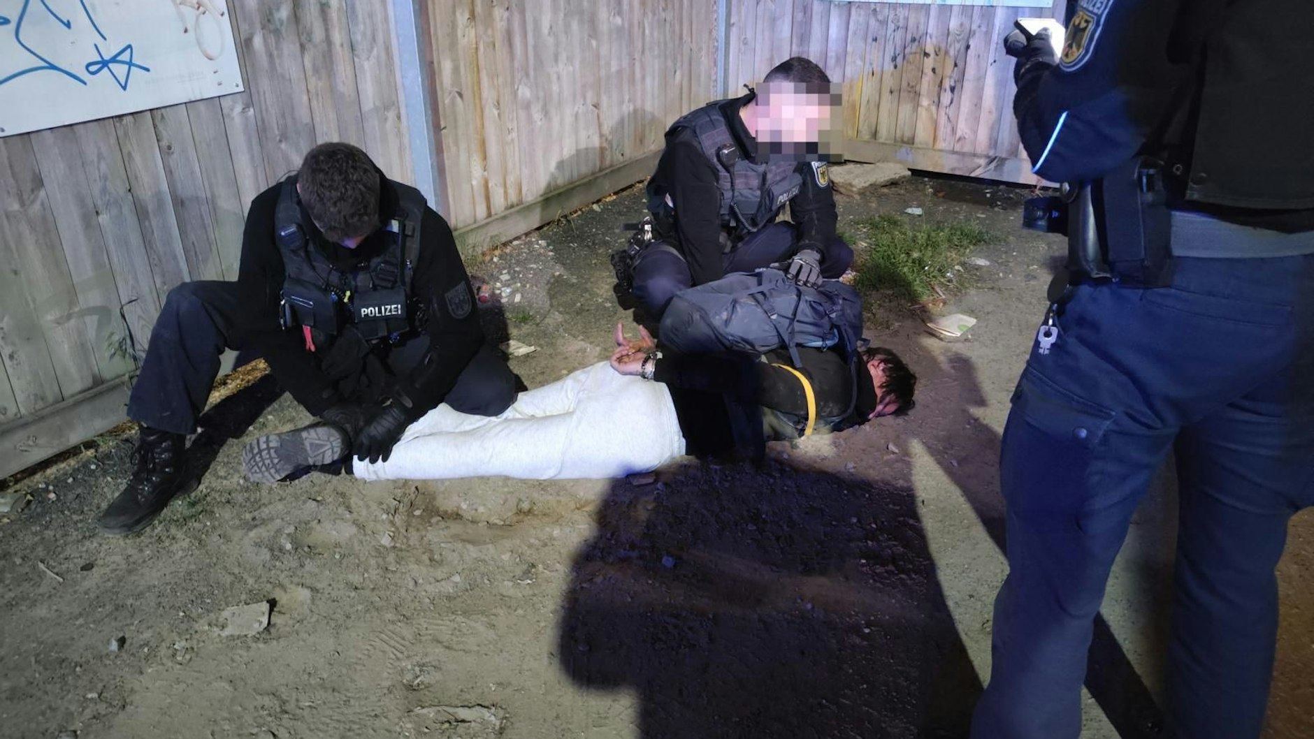 Polizeibeamte halten eine mutmaßliche Tatbeteiligte nach der Attacke in Schöneweide in Schach.