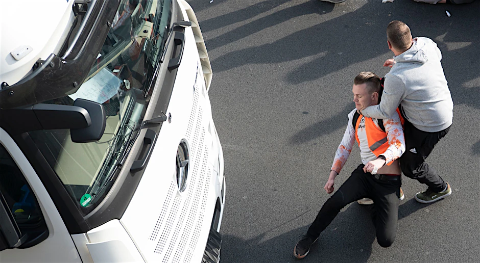 Ein Mann zerrt einen Aktivisten der Gruppe Letzte Generation bei einer Blockade auf der Stadtautobahn A100 unweit des Kurfürstendamm im Würgegriff von der Straße.&nbsp;