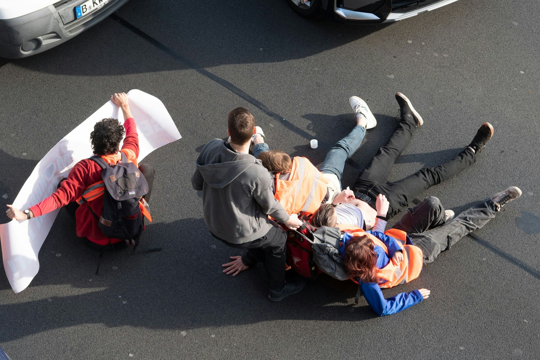 Ein Mann zerrt Aktivisten der Gruppe Letzte Generation bei einer Blockade auf der Stadtautobahn A100 unweit des Kurfürstendamms von der Straße.