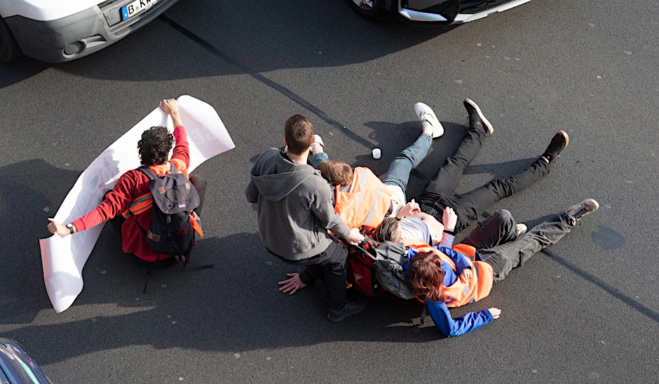 Berlin: Ein Mann zerrt Aktivisten der Gruppe Letzte Generation bei einer Blockade auf der Stadtautobahn A100 unweit des Kurfürstendamms von der Straße.