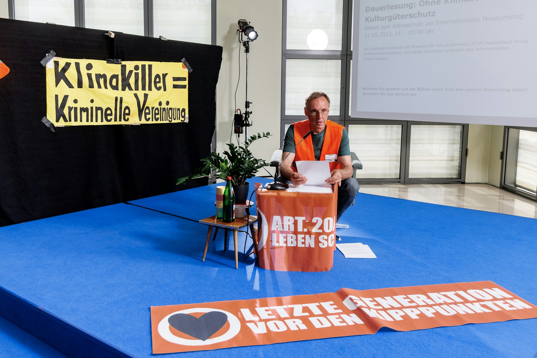 Ein Mann liest im Rahmen einer bundesweiten Kunstperformace der Aktivistengruppe Letzte Generation  im Foyer der Galerie der Gegenwart der Hamburger Kunsthalle.