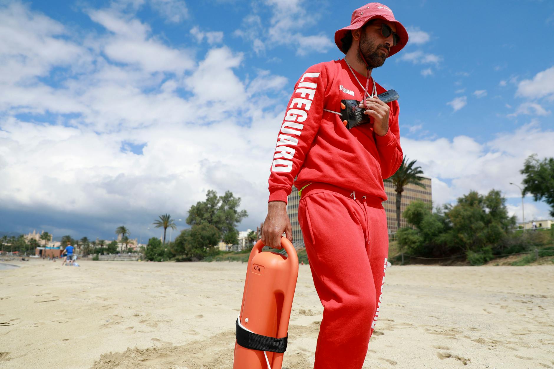 Palma: Nacho, ein Rettungsschwimmer, geht mit einer Rettungsboje in der Hand über den Strand Can Pere Antoni.