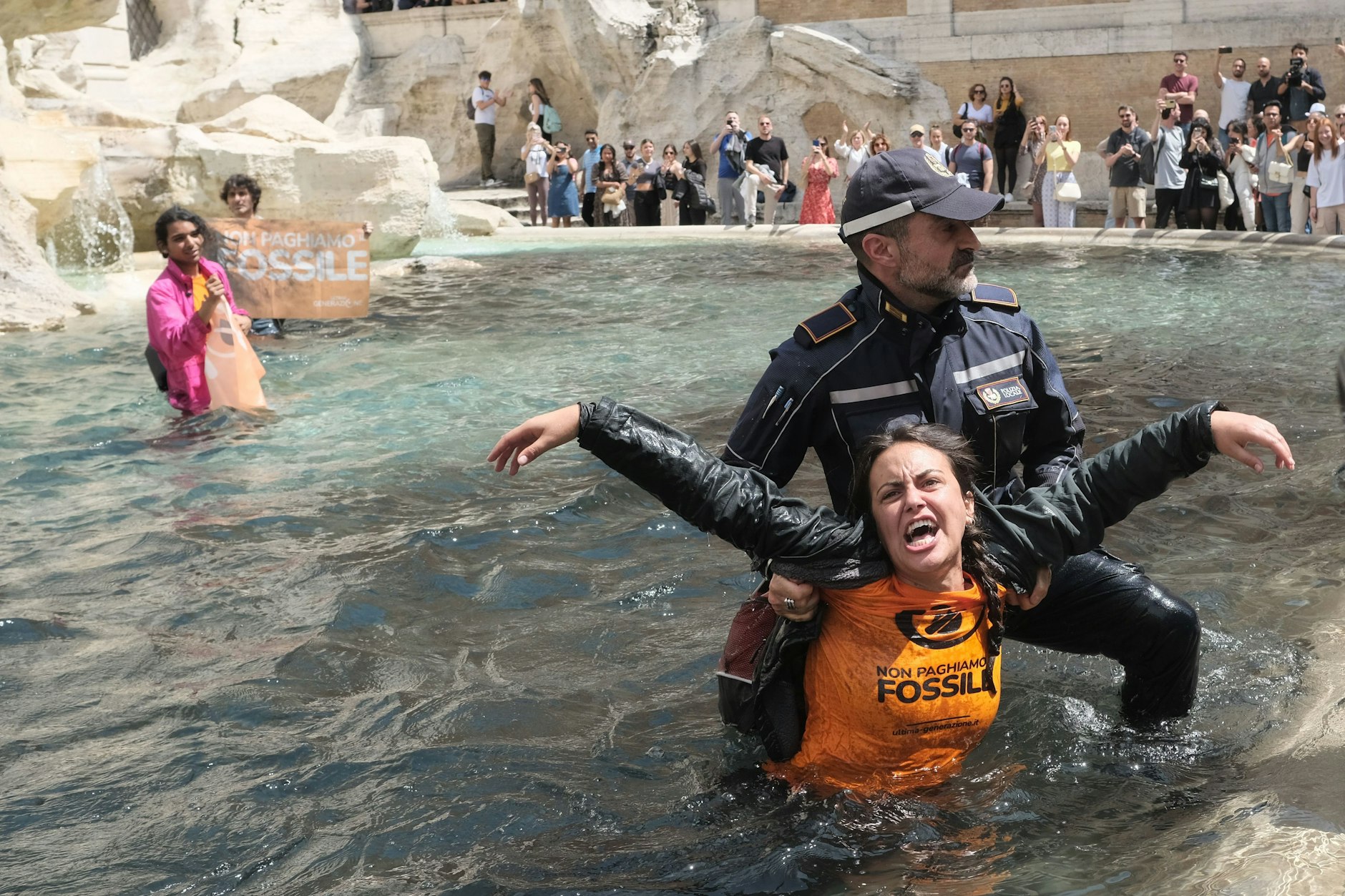 Klimaaktivisten der Letzten Generation werden von Polizisten aus dem Wasser des Trevi-Brunnen geleitet.