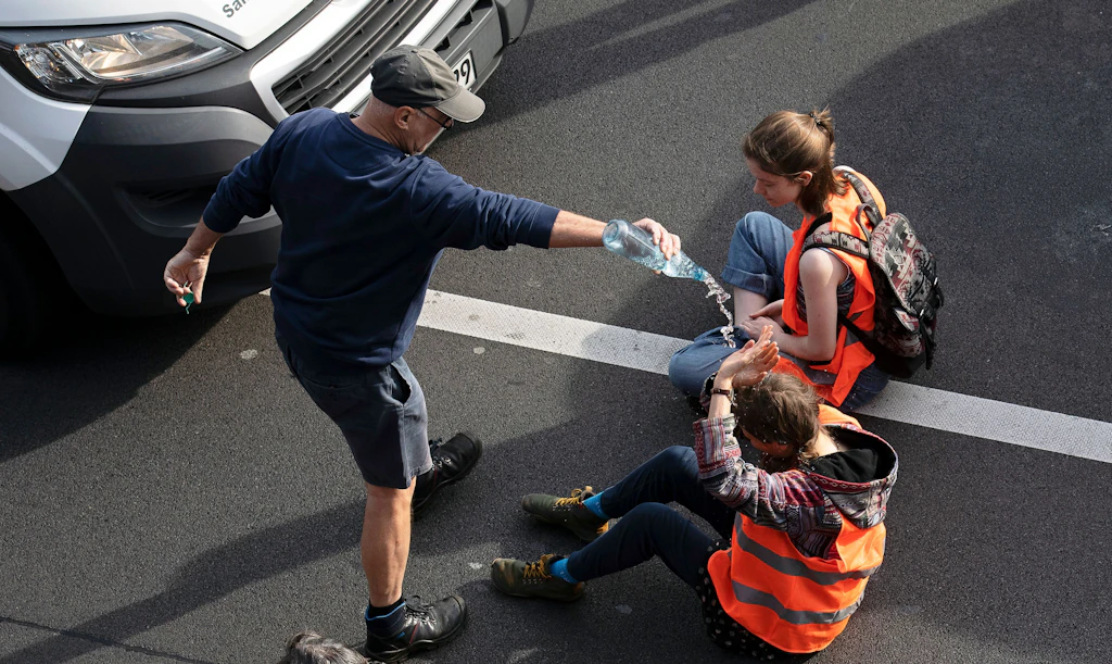 Letzte Generation blockiert Straßen in Berlin: Autofahrer schüttet Flüssigkeit auf Aktivisten