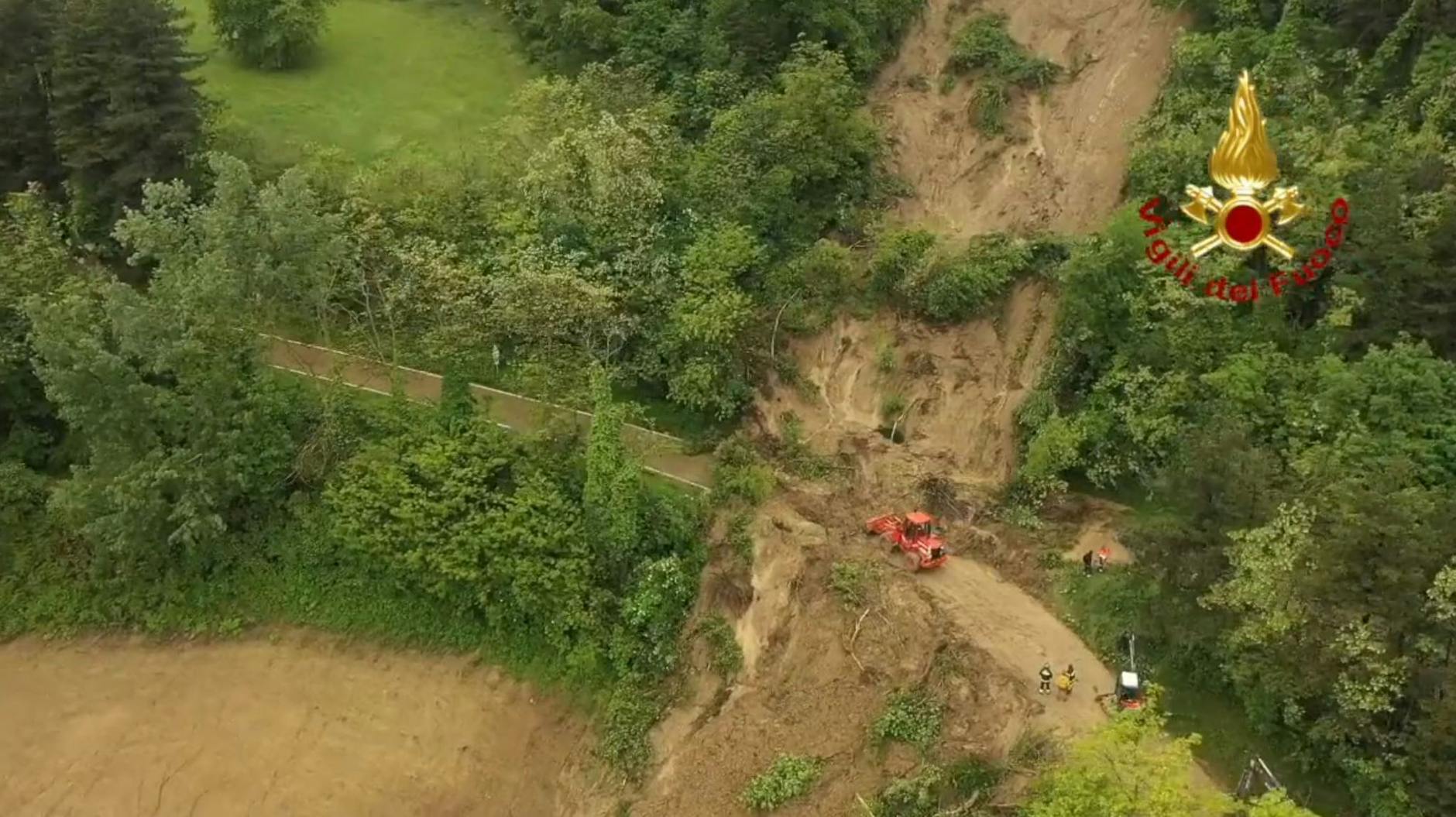 HANDOUT - Mit schwerem Gerät befreit die Feuerwehr nach einem Erdrutsch einen Straßenabschnitt in Norditalien von Schlamm (Aufnahme mit einer Drohne).