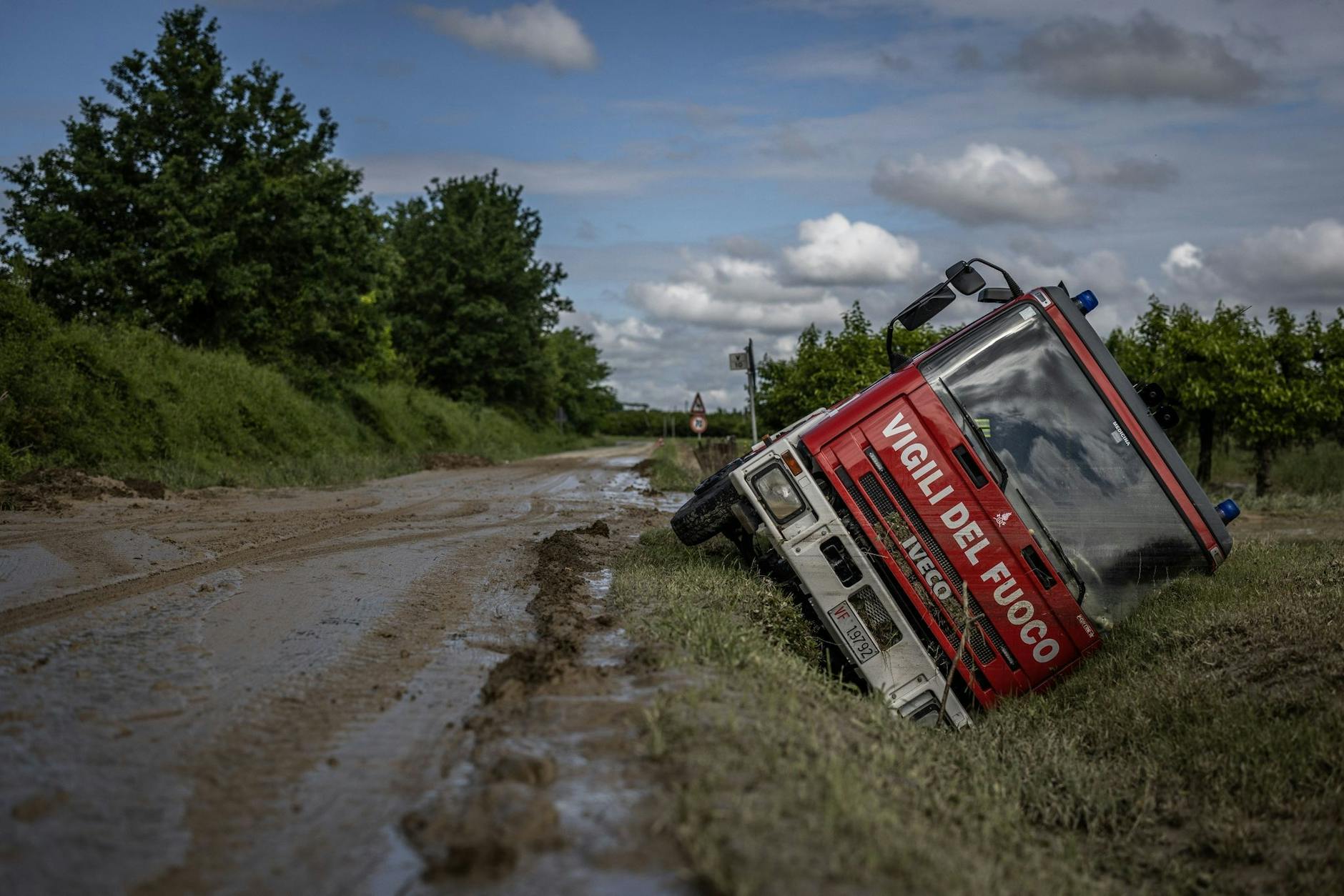 Ein italienisches Feuerwehrauto liegt nach schweren Überschwemmungen in einem Graben.