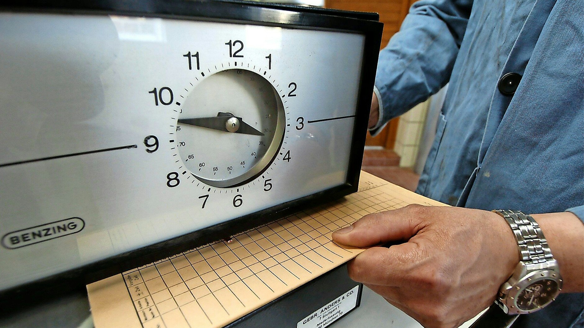 So lief’s früher: Eine Karte zur Arbeitszeiterfassung wird unter eine Stechuhr gelegt.