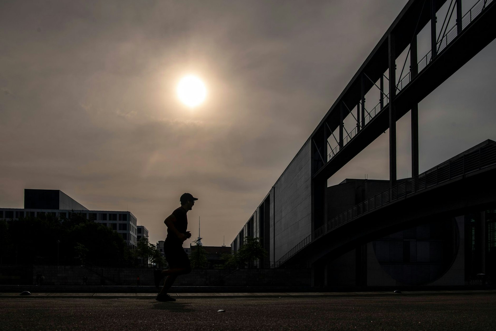 Ein Mann joggt durch das Berliner Regierungsviertel. Die Sonne kämpft sich bis zum Wochenende wieder zurück durch die Wolken.