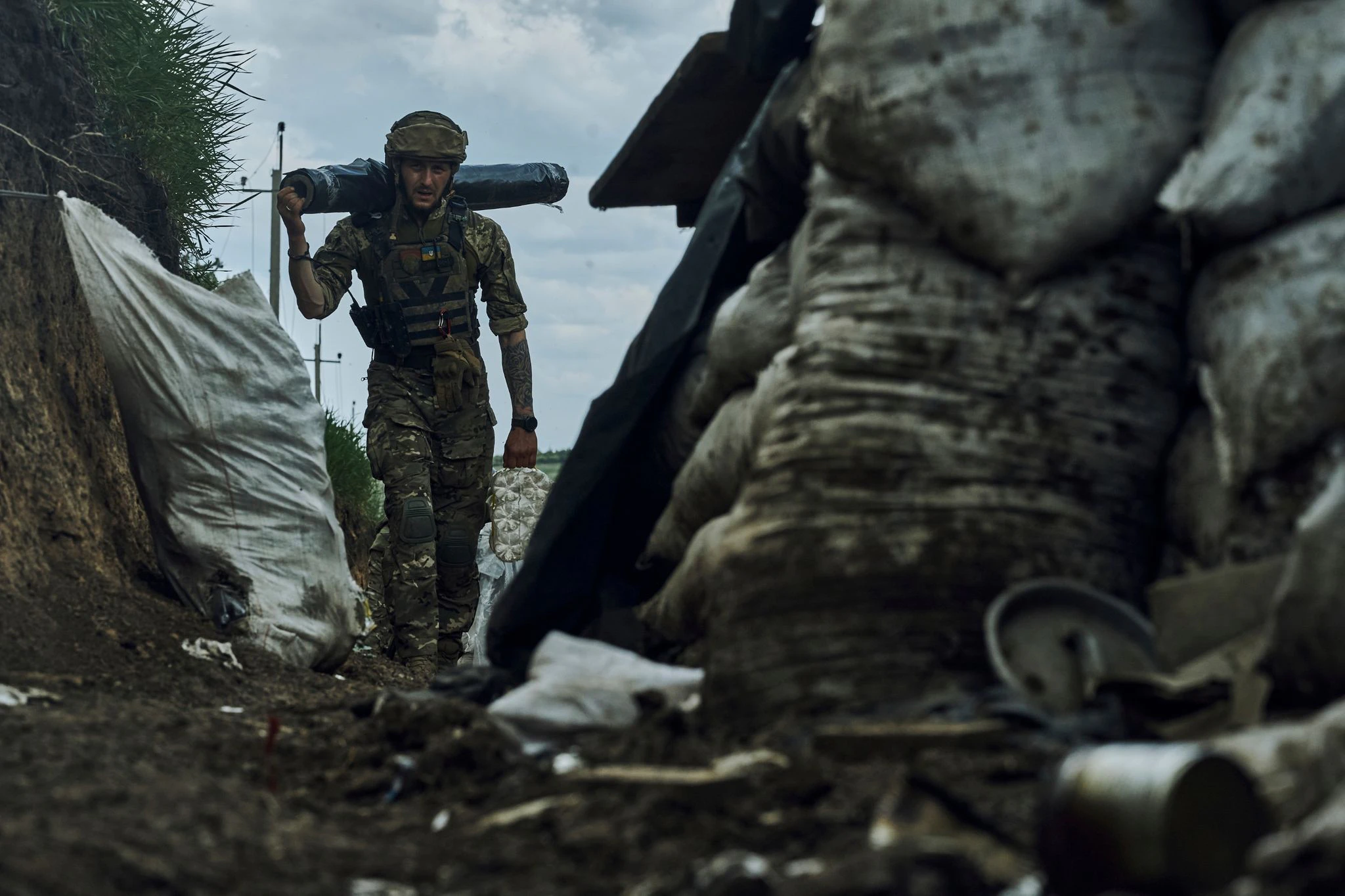 dpatopbilder - Ein ukrainischer Soldat trägt Vorräte in einem Graben an der Frontlinie bei Bachmut.  