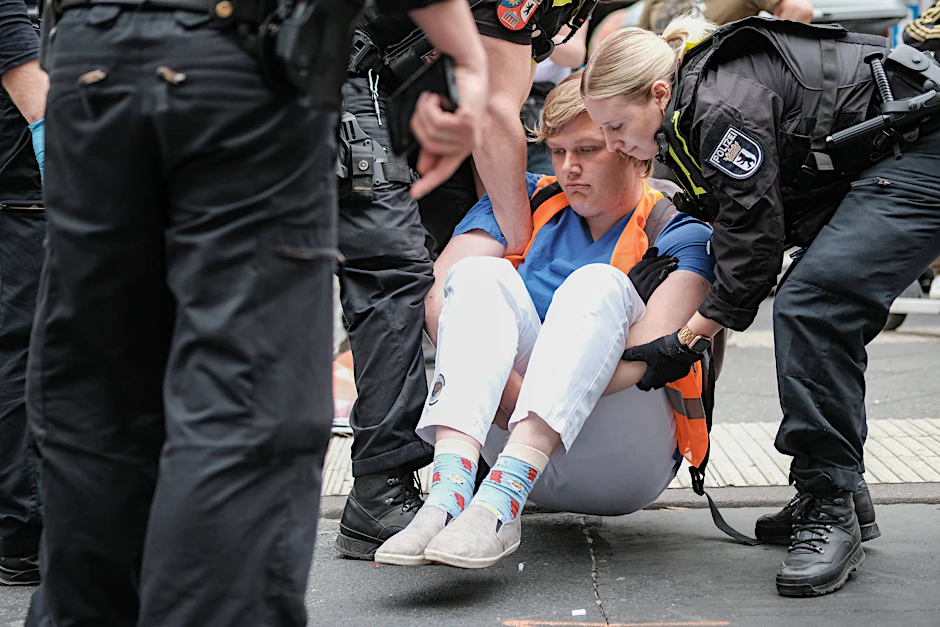Eine Blockade der Letzten Generation in Berlin. Aktivisten müssen weggetragen werden. Wer trägt eigentlich die Kosten?
